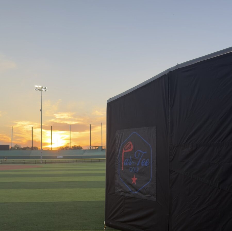 Par-Tee Golf simulator setup beside a baseball field at sunset